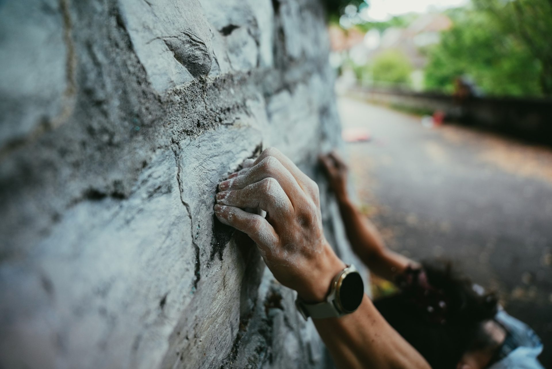 Climber's hands gripping a rough, stone wall.